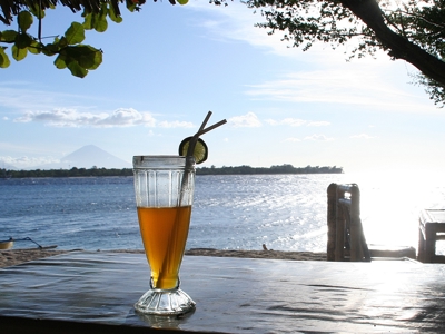 Verfrissend drankje op tafel met uitzicht op zee en zonsondergang tijdens de Route Bali en Lombok, 16 dagen.