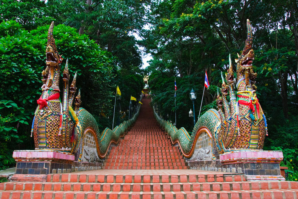 Trap met Naga-slangen bij een boeddhistische tempel in Thailand, omringd door groen.