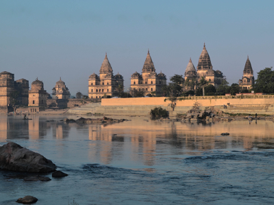 Cenotafen van Orchha langs de Betwa-rivier in Noord-India, met weerspiegeling in het water.
