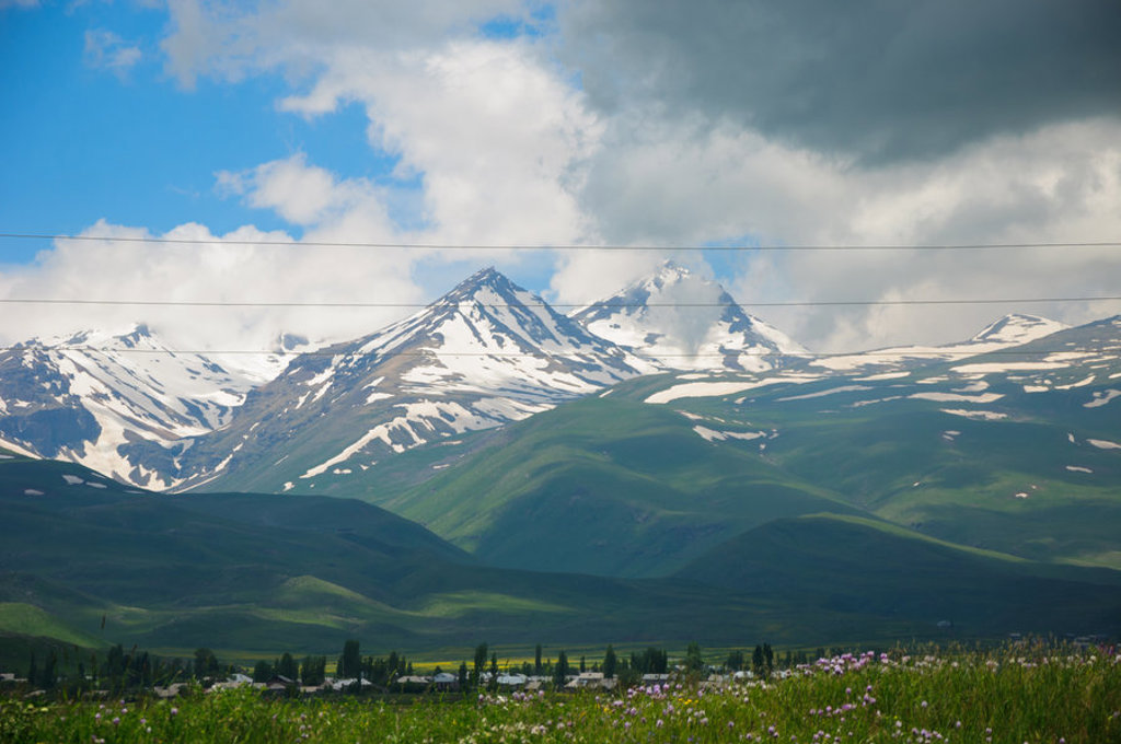 Sneeuwtoppen in het Kaukasusgebergte met groene heuvels, tijdens een groepsrondreis Armenië en Georgië.