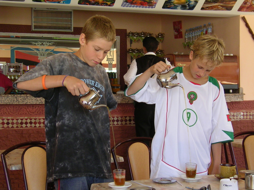 Jongens schenken Marokkaanse muntthee in een café tijdens de familiereis Marokko zomer.