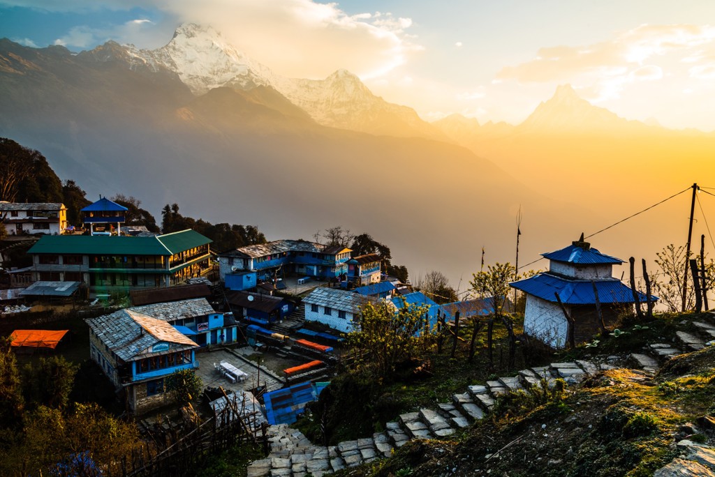 Bergdorp in Nepal bij zonsopkomst met uitzicht op besneeuwde Himalaya-toppen tijdens een 22-35ers groepsrondreis.