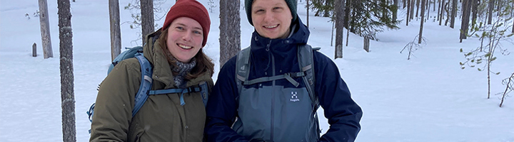 Twee reizigers met rugzak in een besneeuwd bos in Finland tijdens de 22-35ers reis.
