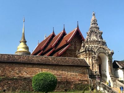 Tempelcomplex met gouden stoepa en sierlijke toegangspoort in Chiang Mai, Thailand.