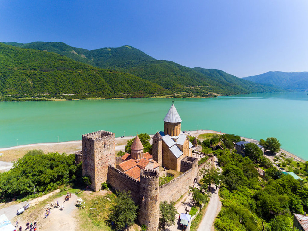 Ananuri-fort en kerk aan het turquoise Zhinvali-stuwmeer in Georgië, omringd door groene bergen.