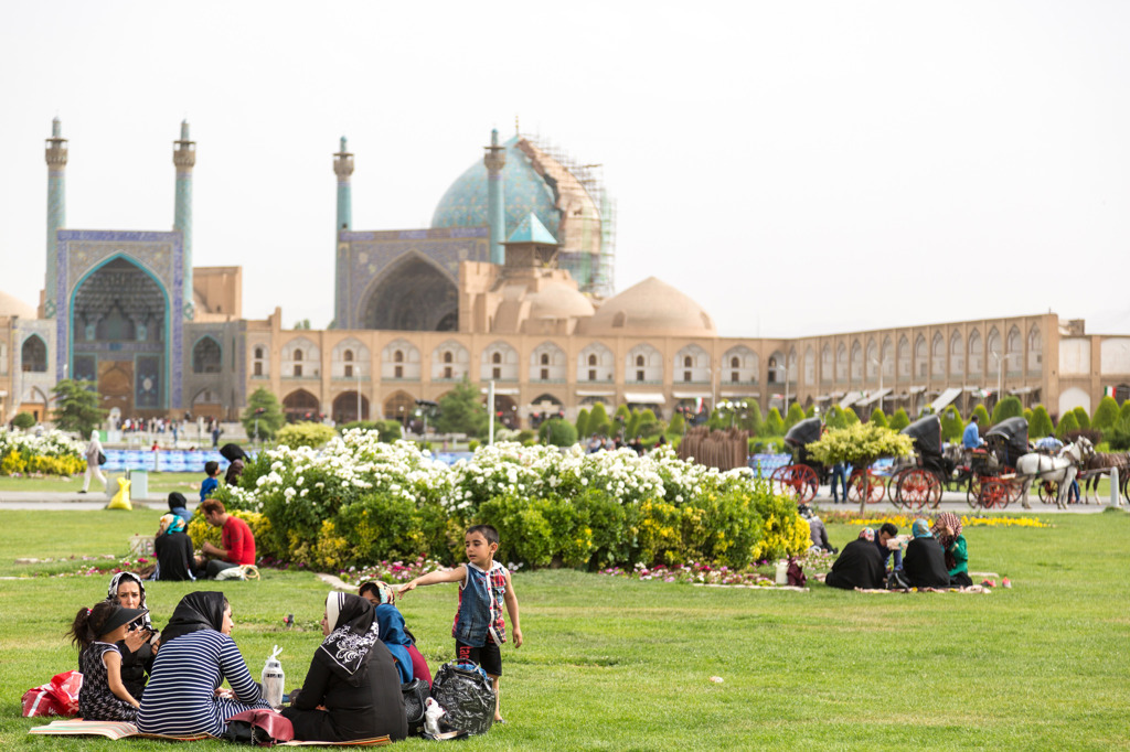 Picknickende families op het gras bij Naqsh-e Jahan-plein in Isfahan, Iran, met de Imam-moskee op de achtergrond.
