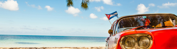 Rode klassieke auto met Cubaanse vlag aan het strand, Cuba.