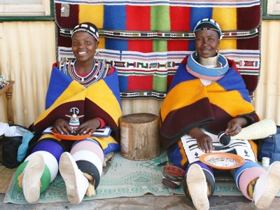 Twee Ndebele-vrouwen in kleurrijke traditionele kleding en kralenkettingen tijdens Route Zuid-Afrika.