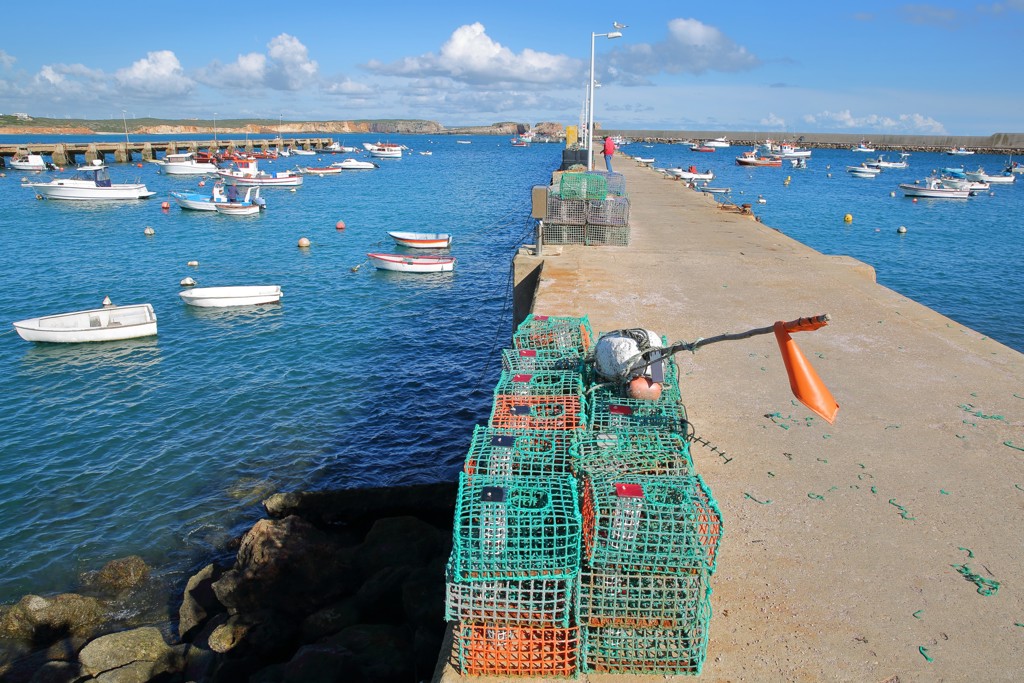 Haven aan de Costa Vicentina met vissersboten en kreeftenfuiken op de pier, Portugal.