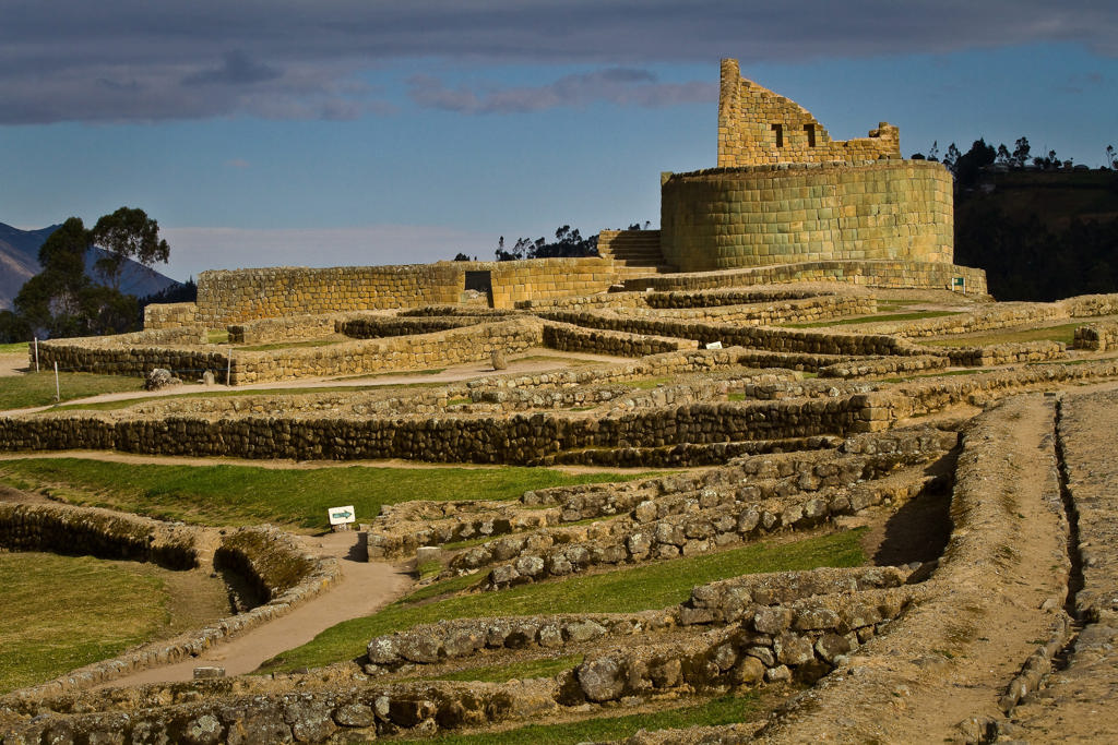 Incaruïnes van Ingapirca in Ecuador, met ronde tempel en stenen terrassen onder een blauwe lucht.