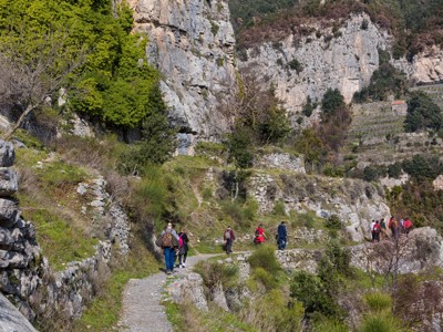 Wandelaars op bergpad langs rotswanden en terrassen aan de Amalfikust in Italië.