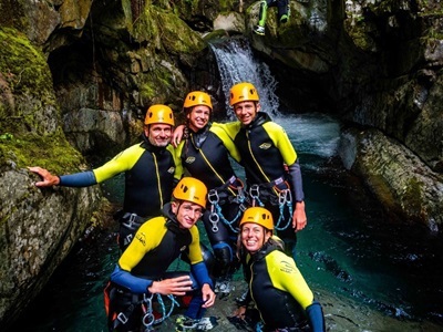 Canyoning in Route Canigou: groep in wetsuits en helmen bij waterval in smalle kloof in de Pyreneeën.
