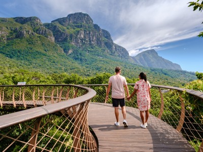 Twee reizigers wandelen over de Boomslang-canopywalk met uitzicht op de bergen bij Kaapstad.