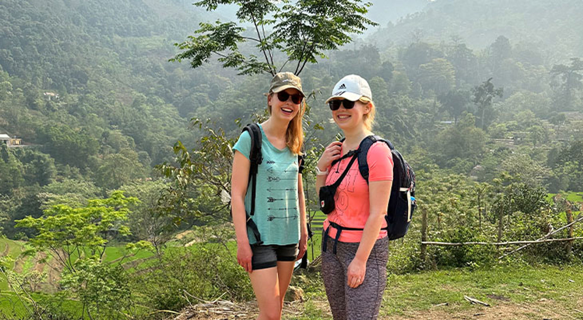 Trekking Da Bac Twee wandelaars met rugzakken poseren bij een groen berglandschap.