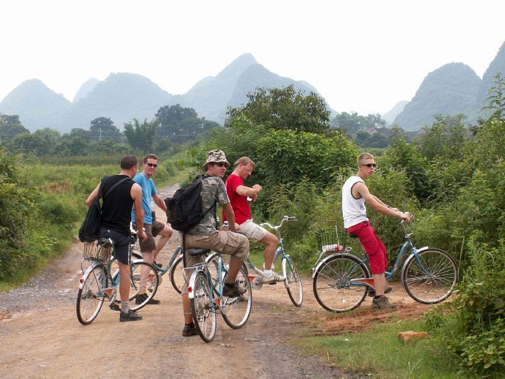Fietsende reizigers tijdens een familiereis China op een landweg tussen groen en karstbergen.