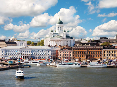 Helsinki haven met de witte Domkerk en veerboten op het water onder een blauwe lucht met wolken.
