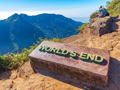 World’s End-uitkijkpunt in Horton Plains, Sri Lanka, met bergpanorama en wandelaar op rotsen.