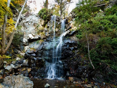 Waterval in het Troödosgebergte op Cyprus, omringd door rotsen en groen.
