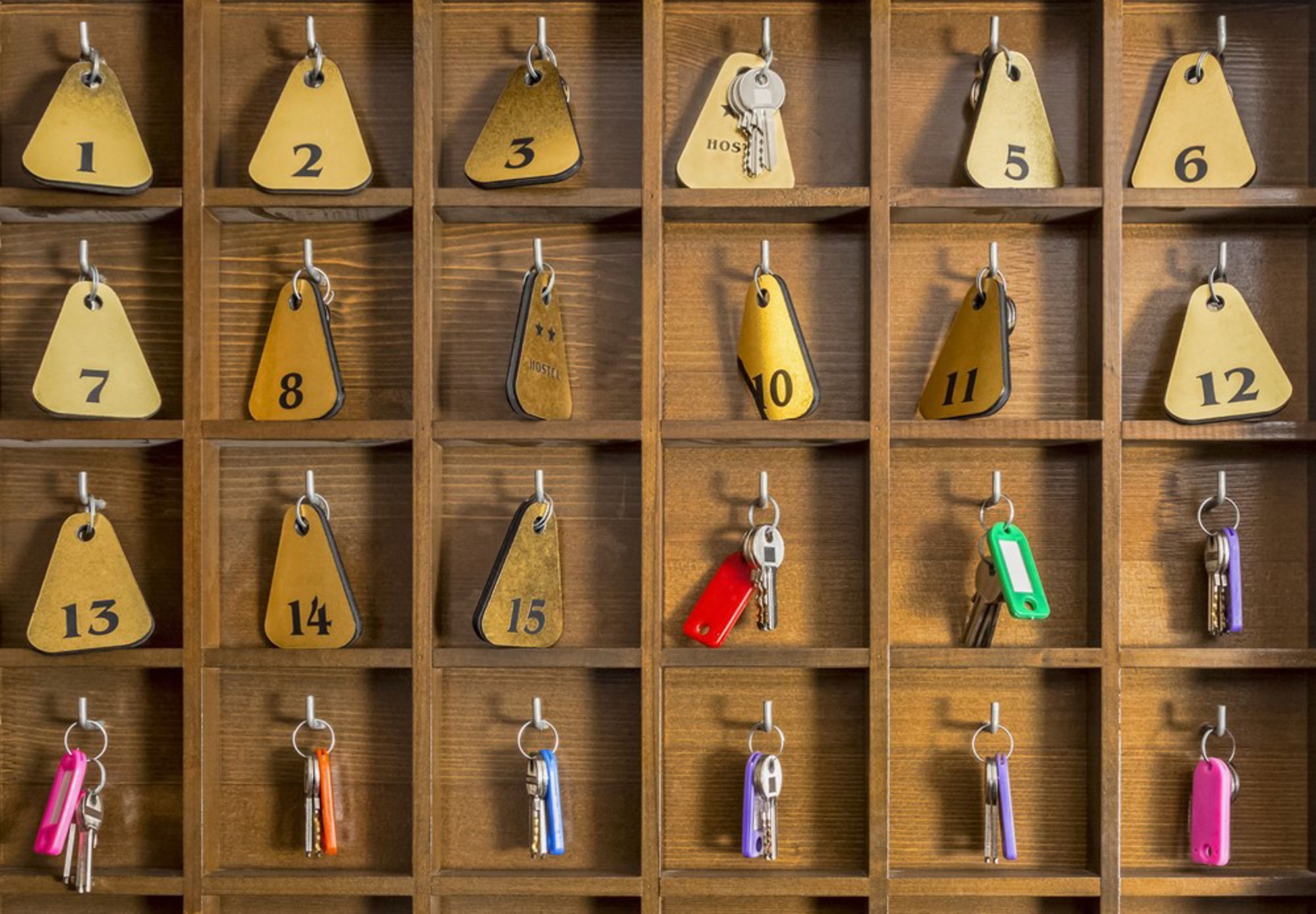 Houten sleutelbord met genummerde labels en sleutels aan haken bij de receptie.