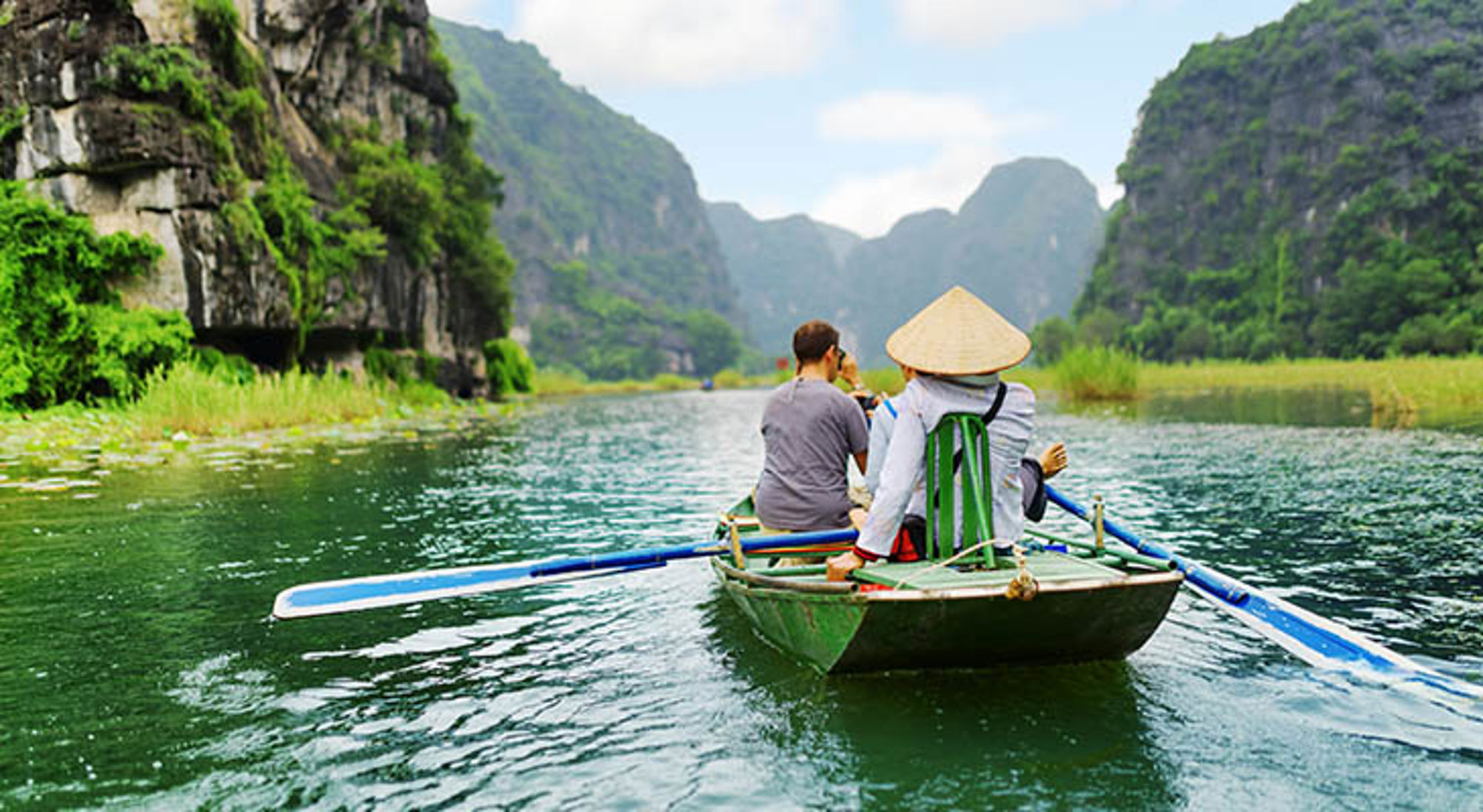 Boottocht door Trang An in Ninh Binh, Vietnam, langs kalksteenrotsen en groene valleien.