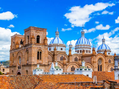 Kathedraal van Cuenca met blauw-witte koepels en oranje dakpannen onder een heldere lucht in Ecuador.