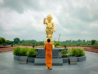 Boeddhistische monnik bij een gouden Boeddhabeeld tijdens festivalreis Noord-India en Nepal.