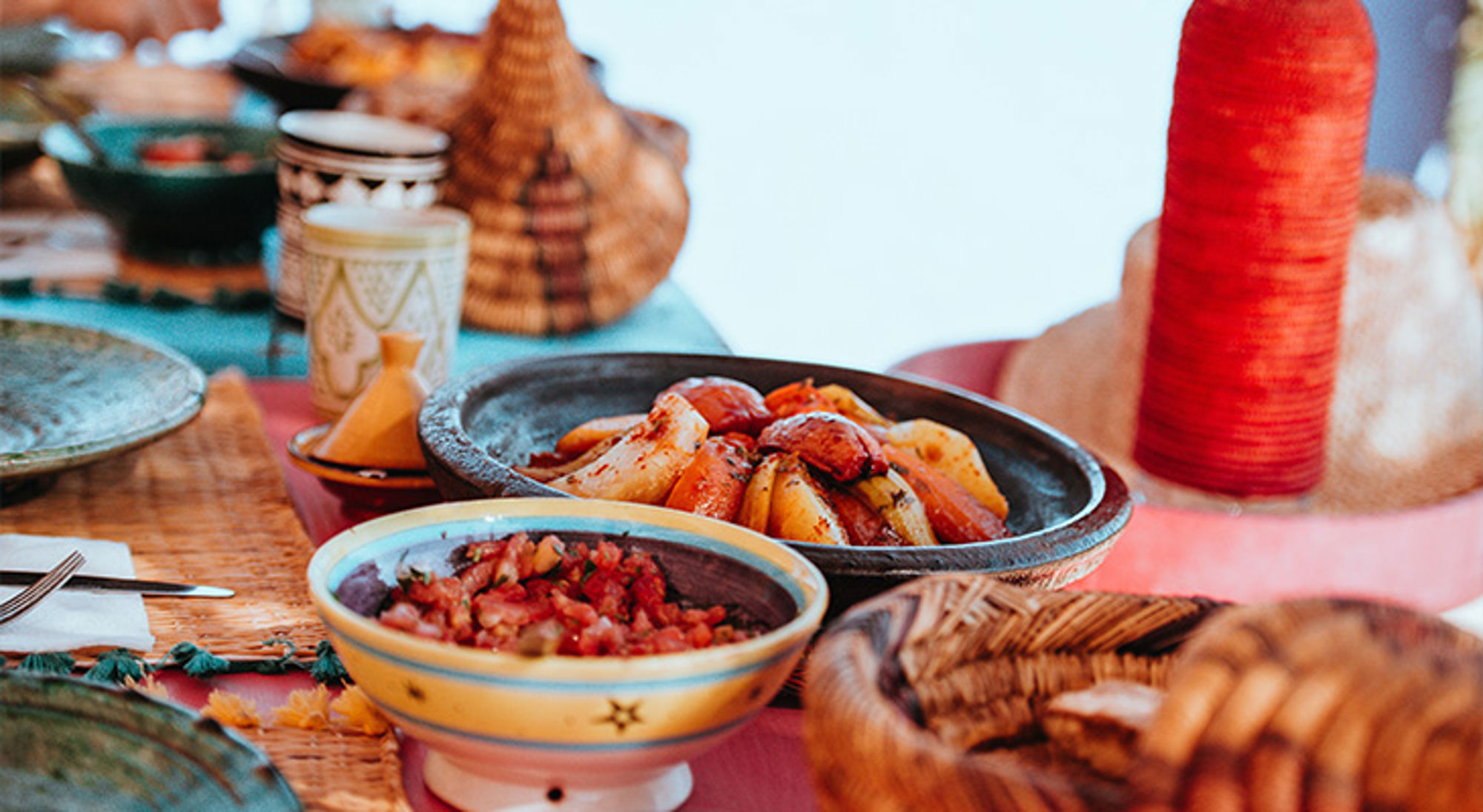 Eten in Marokko Tajine met gestoofde groenten en bijgerechten op een kleurrijk gedekte tafel.