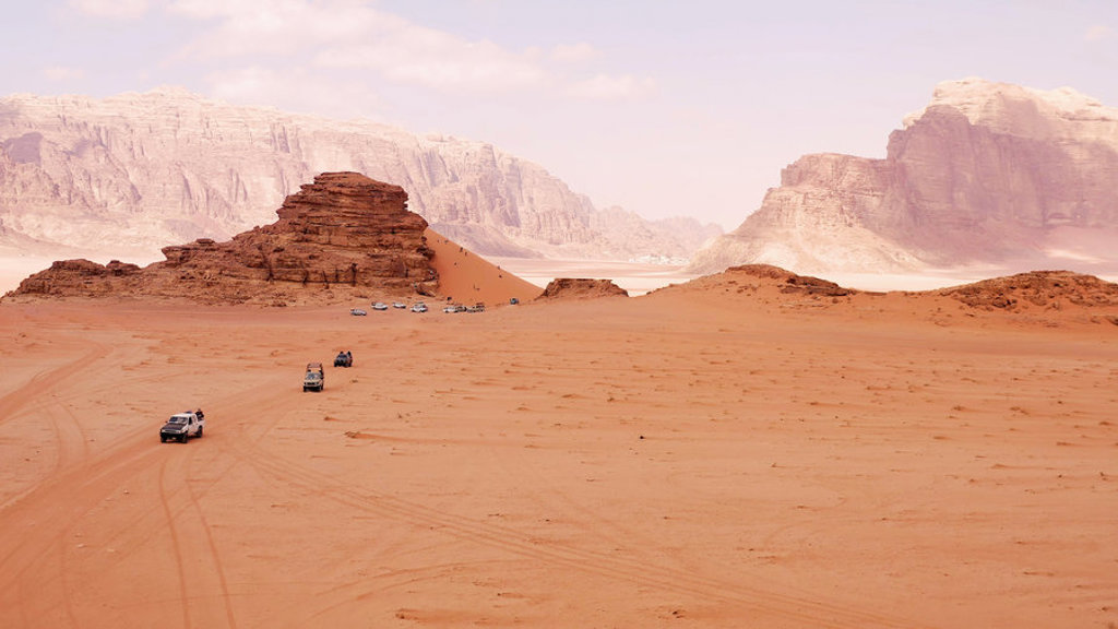 Jeepsafari door de Wadi Rum-woestijn in Jordanië, met zandduinen en rotsformaties op de achtergrond.