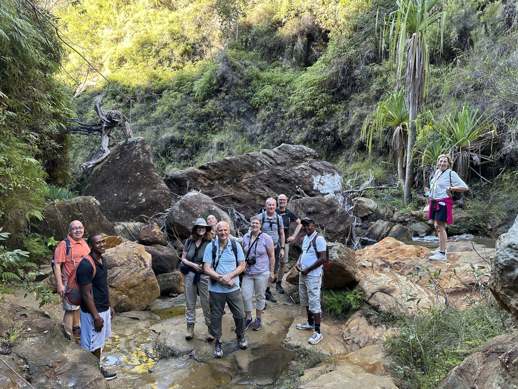 Groep wandelaars tijdens een groepsrondreis Madagascar in een groene kloof met rotsen en een beekje.