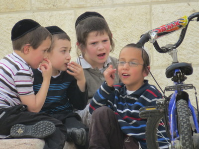 Joodse jongens met keppeltje zitten samen en praten naast een fiets in Israël.