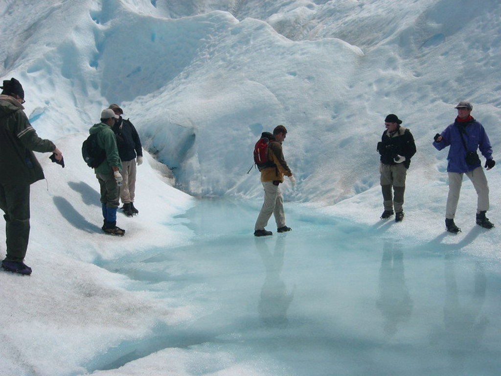 Wandelaars op een gletsjer met azuurblauw smeltwater tijdens een groepsrondreis Patagonië.