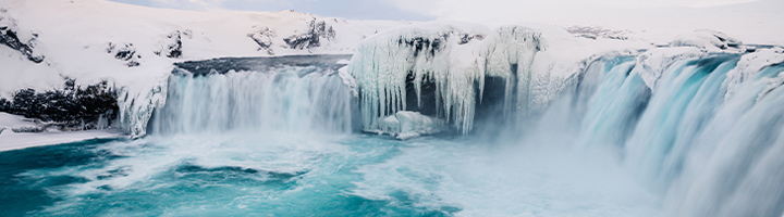 Bevroren waterval in Noord-IJsland met ijskliffen en turquoise water tijdens een winterse groepsreis.