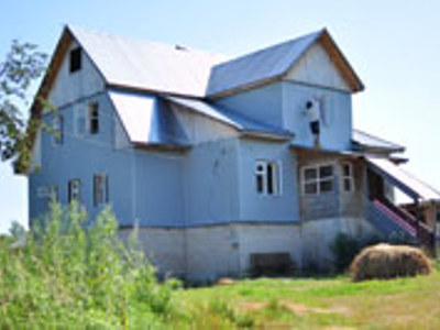 Houten landhuis op het Russische platteland, omringd door groen.