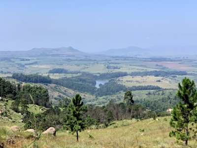 Uitzicht over glooiende heuvels en groene valleien met een meer in Zuid-Afrika.