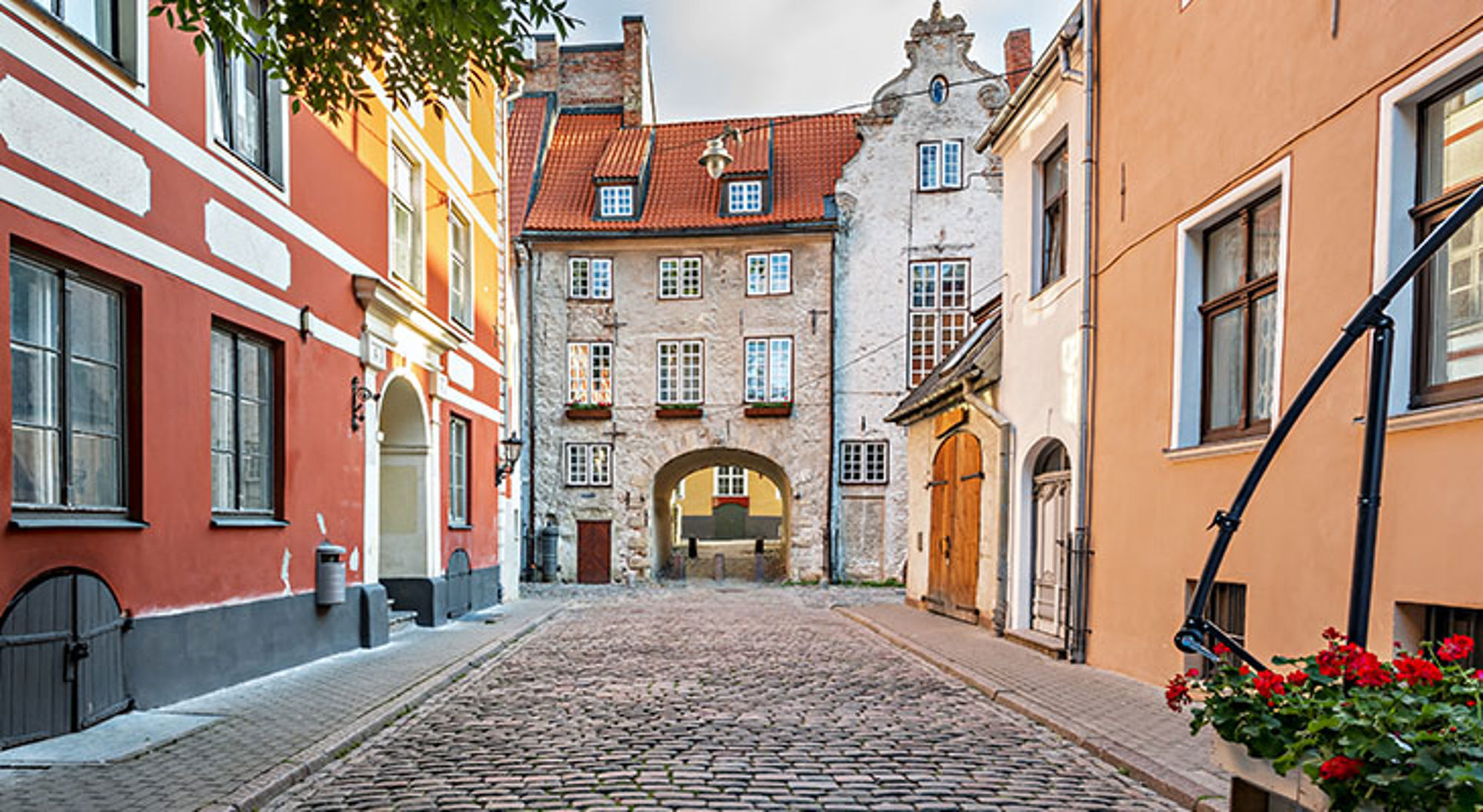 Gekleurde gevels langs een geplaveide straat met historische poort in de oude binnenstad van Tallinn, Estland.