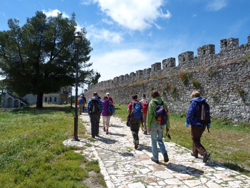 Wandelaars tijdens groepsrondreis Albanië bij een oude stadsmuur op een zonnig pad.