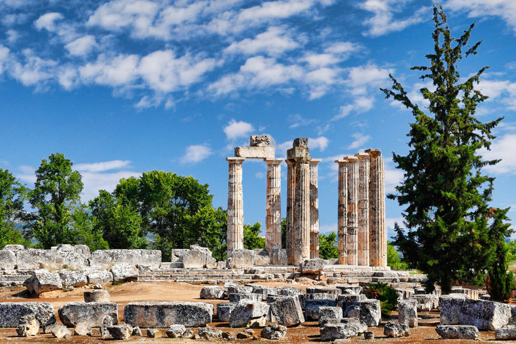 Ruïnes van de Tempel van Zeus in Nemea, Griekenland, onder een blauwe lucht.