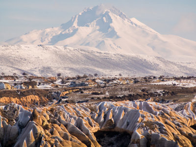 Sneeuw op de rotsformaties van Cappadocië met de besneeuwde vulkaan Erciyes op de achtergrond.