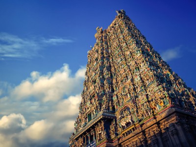 Gopuram van een Zuid-Indiase hindoeïstische tempel met kleurrijke beelden tegen een blauwe lucht.