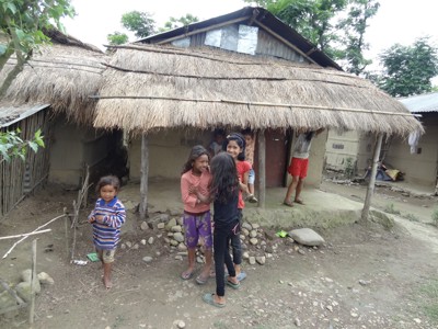 Kinderen spelen voor een traditioneel huis met rieten dak tijdens de Route Nepal Familiereis 15 dagen, .