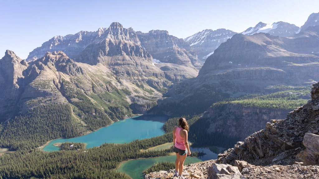 Wandelaar met uitzicht op turquoise bergmeer en ruige Rocky Mountains in West-Canada.