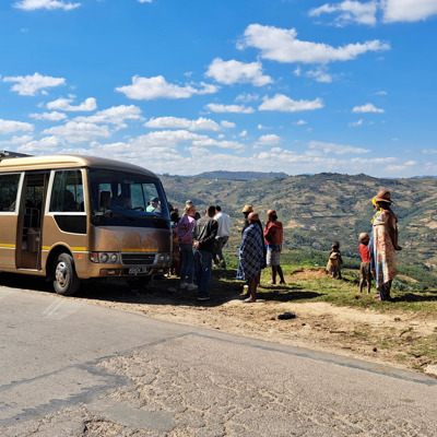 Groepsrondreis Madagascar: busstop met reizigers bij uitzichtpunt over terrassen en heuvels.