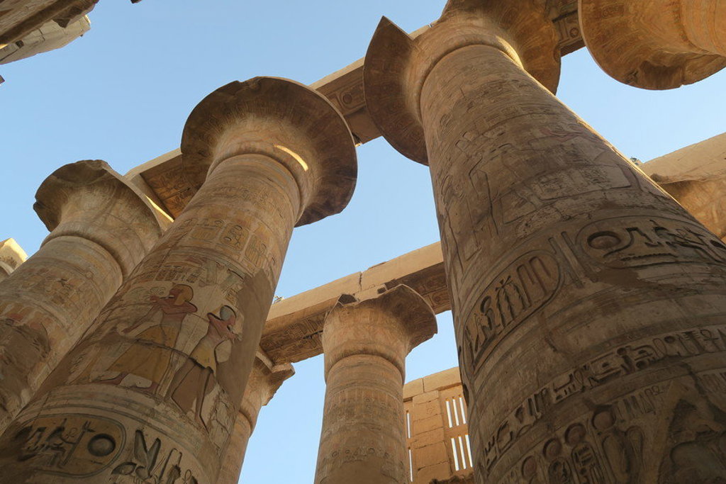 Hoge tempelzuilen met hiërogliefen in Egypte, gezien van onderaf tijdens een groepsrondreis.