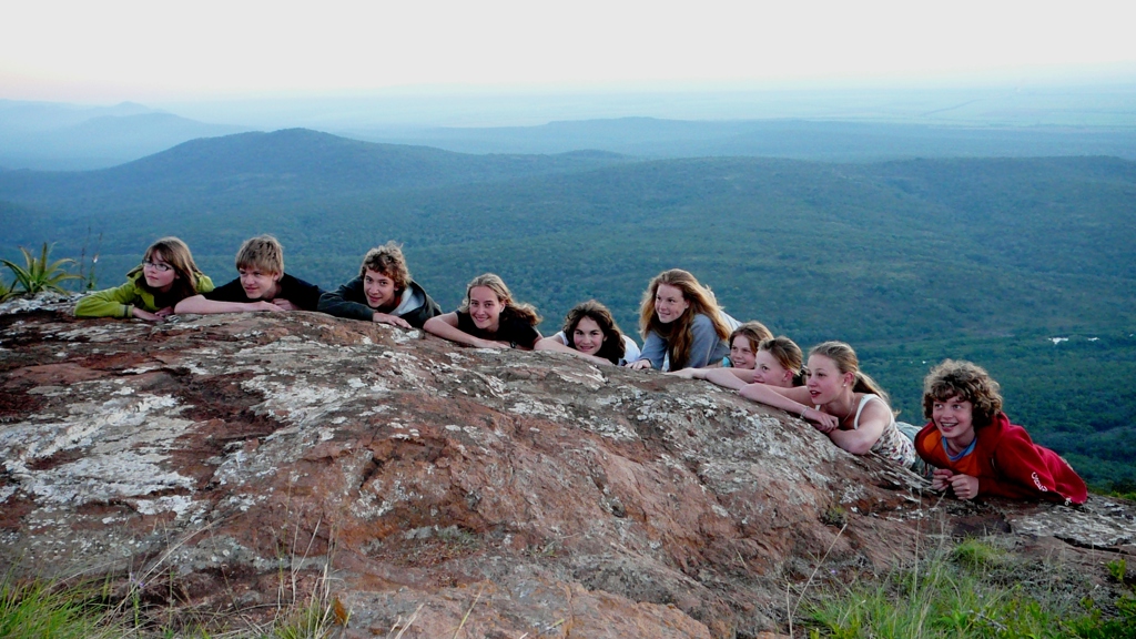 Kindergroep op een rots met uitzicht over het groene heuvellandschap tijdens familiereis Zuid-Afrika en eSwatini.