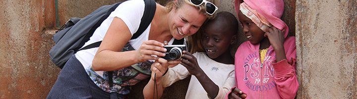 Reisbegeleidster Marion Roest bekijkt samen met twee kinderen foto’s op een digitale camera.