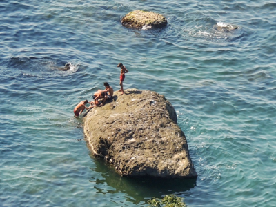 Kinderen spelen op een rots in zee aan de Zwarte Zeekust in Georgië.