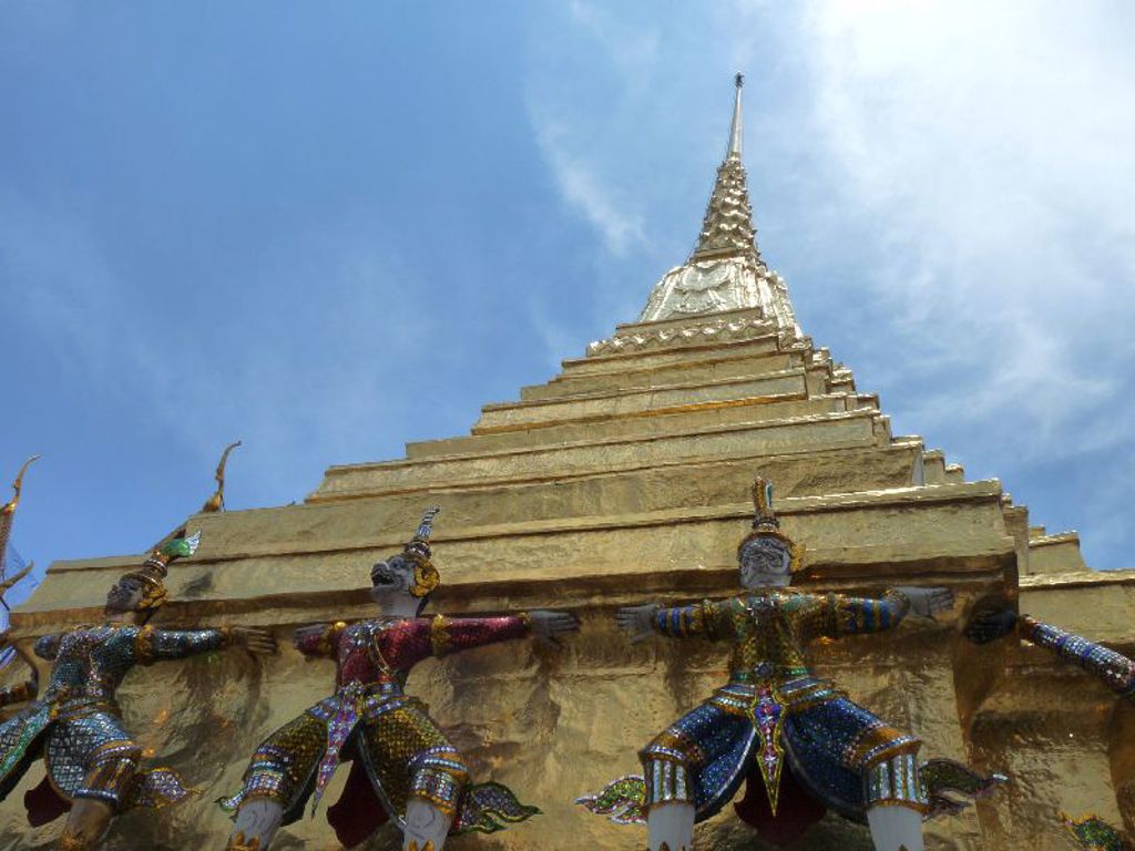 Gouden stoepa met kleurrijke tempelwachters bij een boeddhistische tempel in Thailand tijdens een groepsrondreis.
