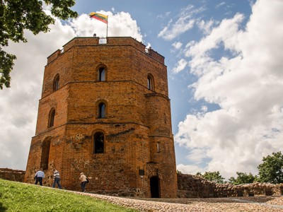Gediminastoren in Vilnius met Litouwse vlag onder een blauwe lucht met wolken.
