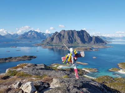 Uitzicht over de Lofoten in Noorwegen met bergmassief, eilanden en helderblauw water vanaf een rotsachtige heuveltop.
