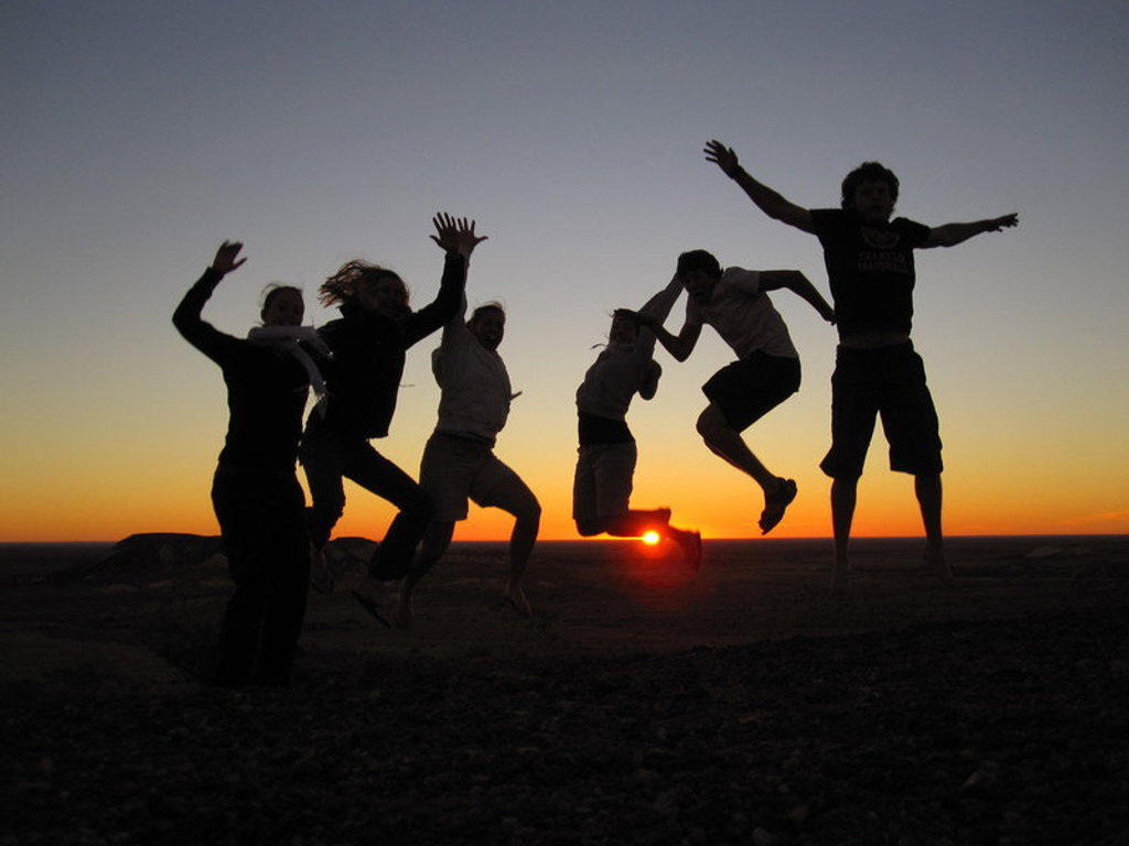 Groep reizigers springt als silhouet bij zonsondergang tijdens groepsrondreis Australië & Nieuw-Zeeland.